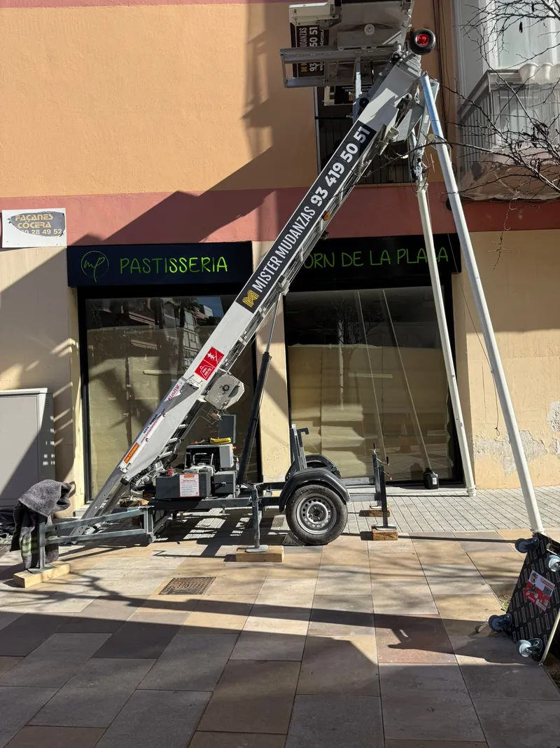 Plataforma elevadora de mudanzas montada sobre la acera con los estabilizadores desplegados
